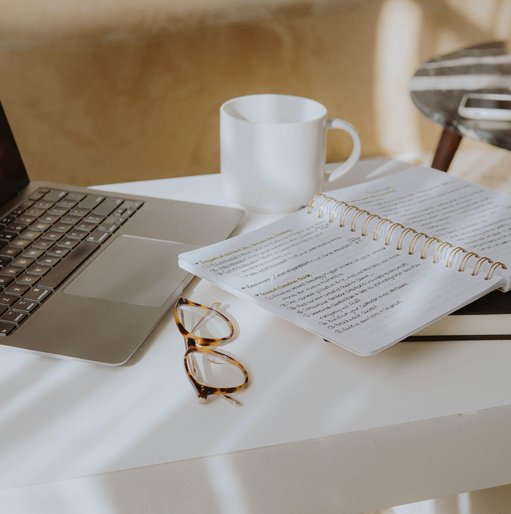 Laptop, notebook, mug and glasses