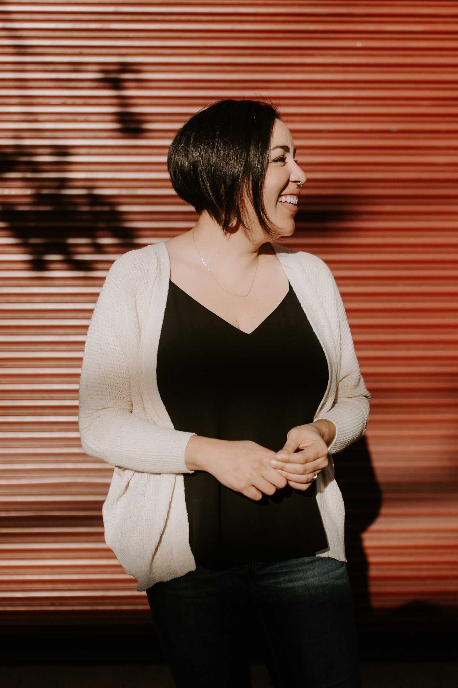 Donaji stands outside in front of a dark orange background